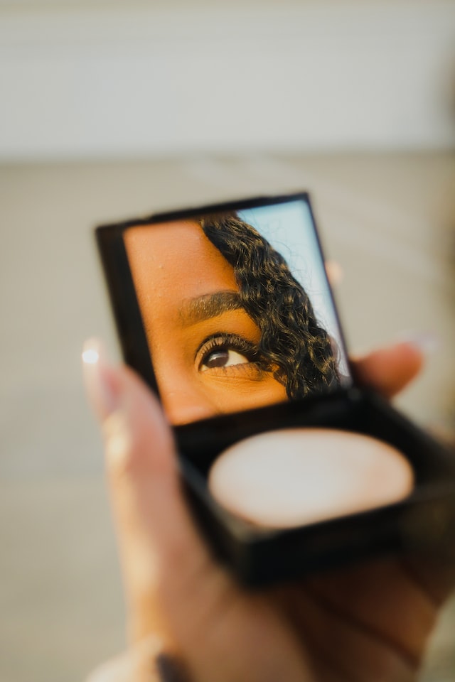 person holding concealer with mirror