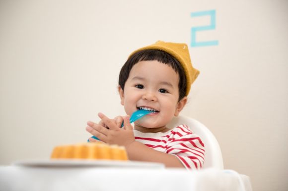 Highchair - baby sitting on white chair while smiling at the camera