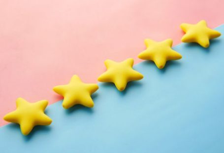 Reviews - a row of yellow stars sitting on top of a blue and pink surface