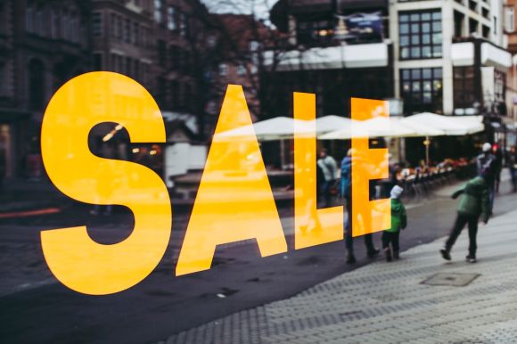 Discount - man in green jacket walking on sidewalk during daytime