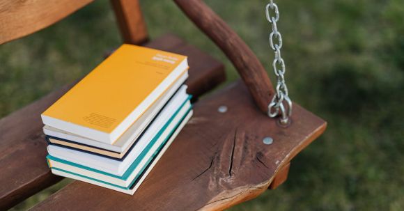 Poetry Collection - From above of pile of colorful books on wooden bench of garden swing on quiet summer evening