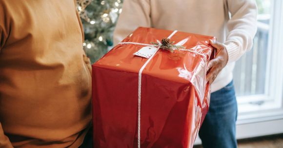Fitness Gifts - Crop anonymous African American father giving big present box to teen son during festive celebration at home