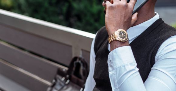 Outdoor Watches - A Man Sitting on a Bench While on a Phone Call